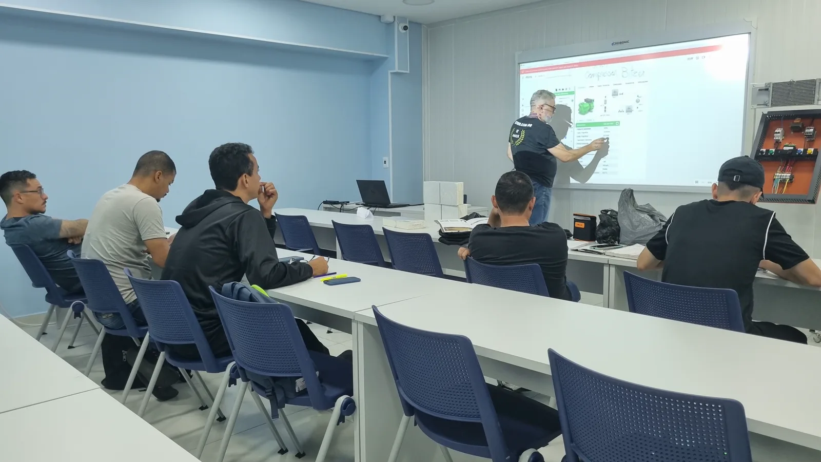 Instrutor conduzindo uma aula técnica de refrigeração para uma turma